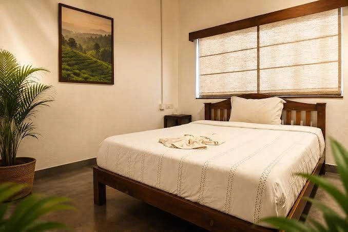 Comfortable double bedroom with wooden furniture and warm lighting at a resort in Munnar.